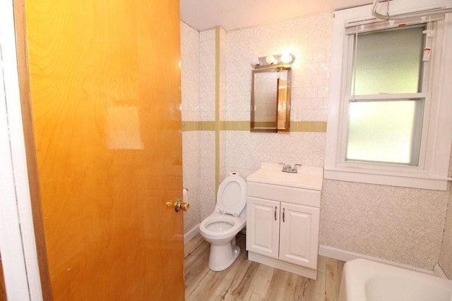 bathroom featuring toilet, hardwood / wood-style floors, a bathtub, tile walls, and vanity