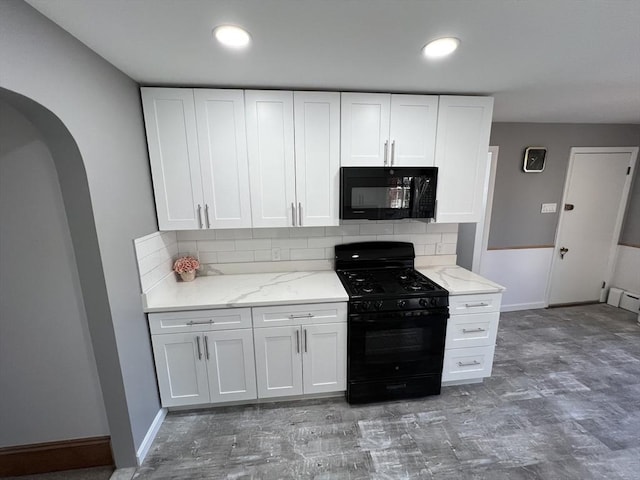 kitchen featuring black appliances, backsplash, light stone counters, and white cabinetry