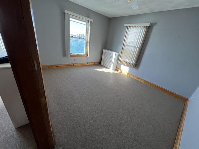 unfurnished room featuring ceiling fan, a healthy amount of sunlight, and radiator heating unit