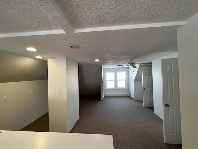 spare room featuring ceiling fan, dark colored carpet, a baseboard radiator, lofted ceiling, and a textured ceiling