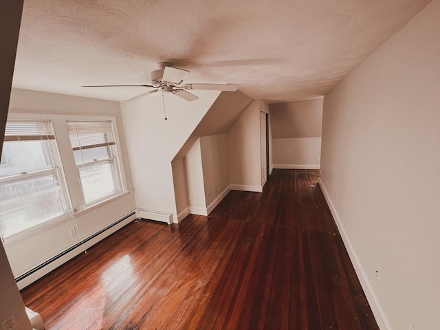 additional living space with dark wood-type flooring, baseboard heating, ceiling fan, and vaulted ceiling