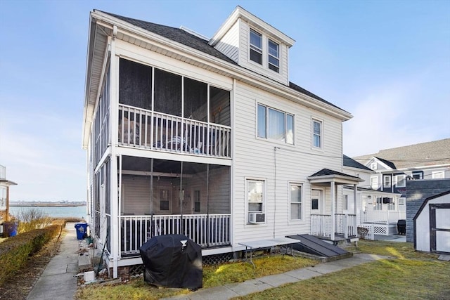 rear view of house featuring cooling unit, a water view, and a yard