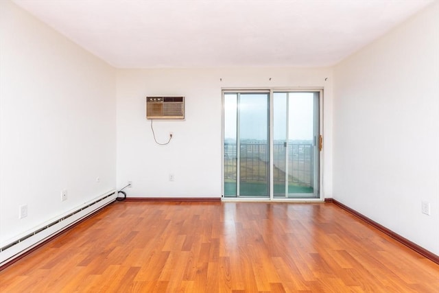 unfurnished room featuring a baseboard heating unit, light wood-style floors, baseboards, and a wall mounted AC