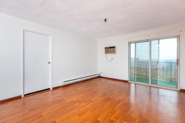 empty room featuring a baseboard heating unit, light wood finished floors, a wall mounted AC, and baseboards