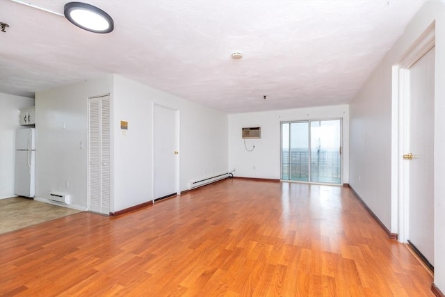 unfurnished room featuring light wood-style flooring, a baseboard heating unit, baseboards, baseboard heating, and a wall mounted air conditioner