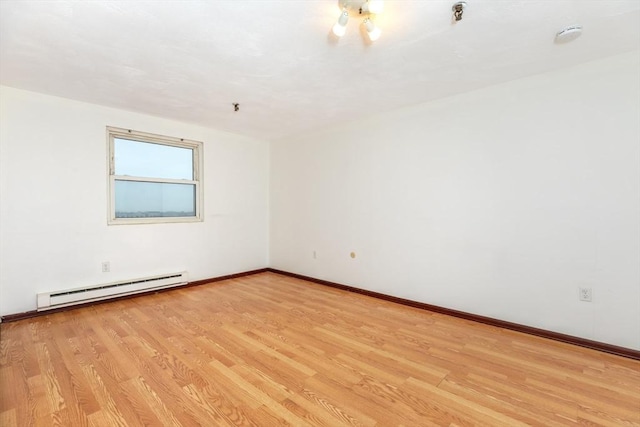 empty room featuring light wood-type flooring, baseboards, and baseboard heating