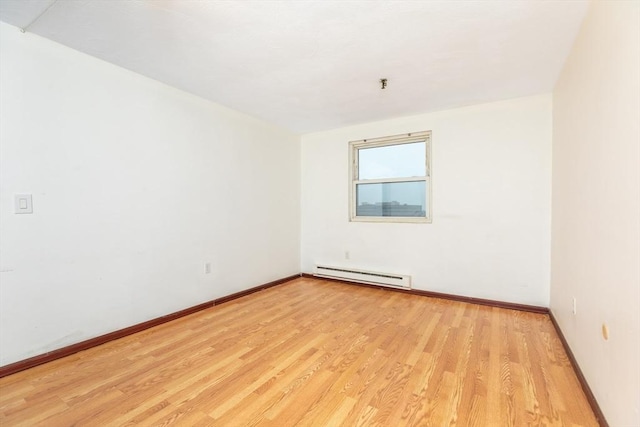 spare room featuring baseboard heating, light wood-style flooring, and baseboards