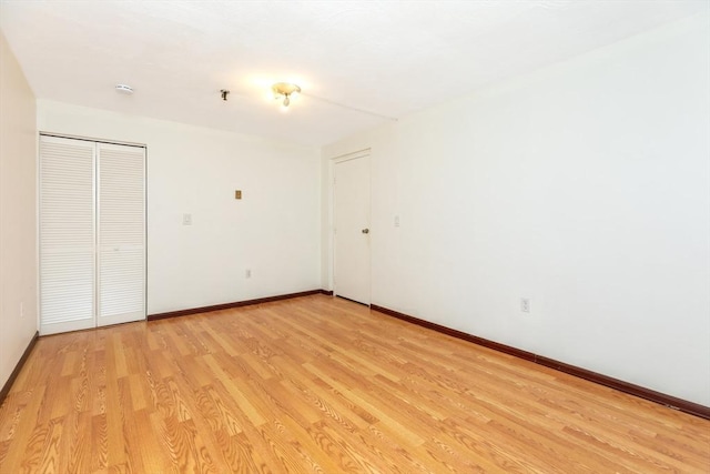 unfurnished bedroom featuring a closet, light wood-type flooring, and baseboards