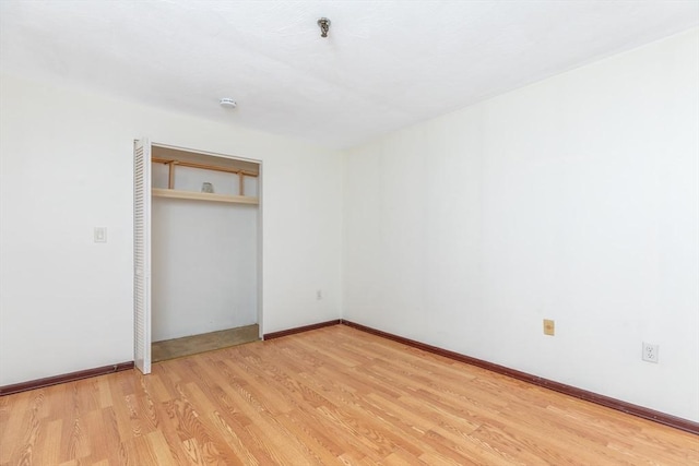 unfurnished bedroom with light wood-style flooring, baseboards, and a closet