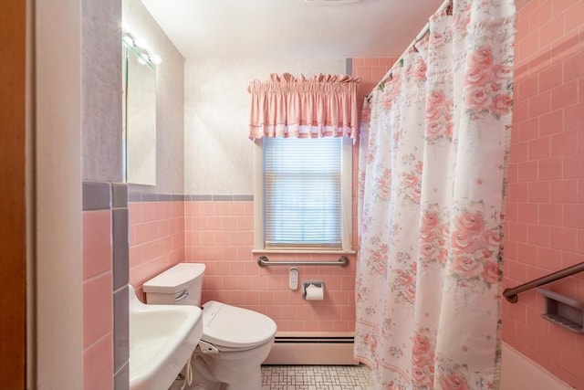 bathroom with a shower with curtain, tile walls, toilet, a sink, and baseboard heating