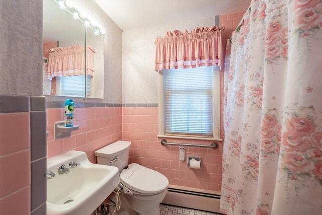 full bath with a wainscoted wall, toilet, a sink, a baseboard radiator, and tile walls