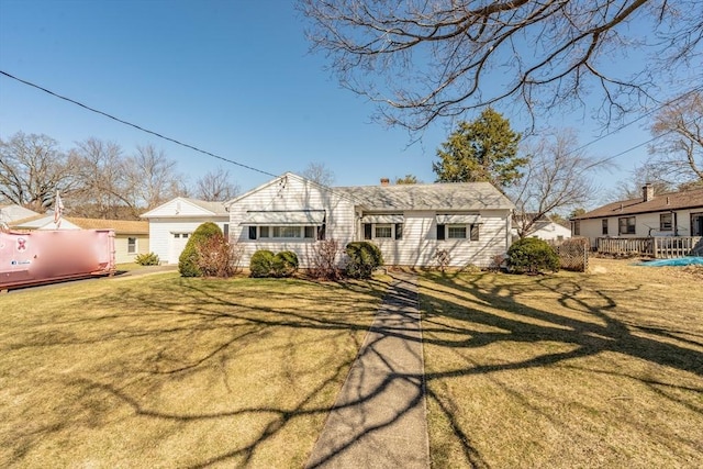 view of front of property with an attached garage, a chimney, and a front yard