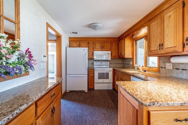 kitchen featuring white appliances, light stone countertops, brown cabinets, and a sink