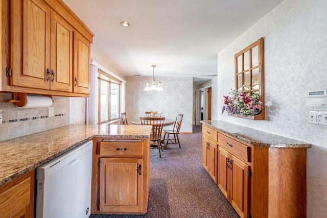 kitchen featuring a peninsula, wallpapered walls, white dishwasher, an inviting chandelier, and dark colored carpet