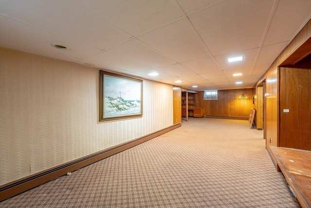 hall with a baseboard radiator, baseboards, wallpapered walls, a drop ceiling, and light colored carpet