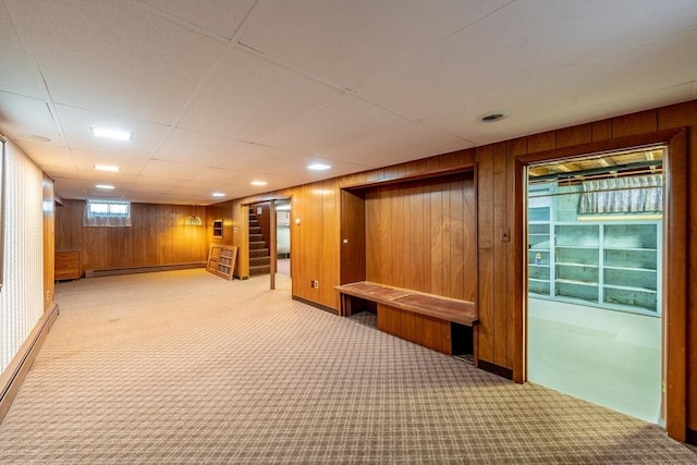 interior space with carpet floors, wooden walls, and a baseboard heating unit