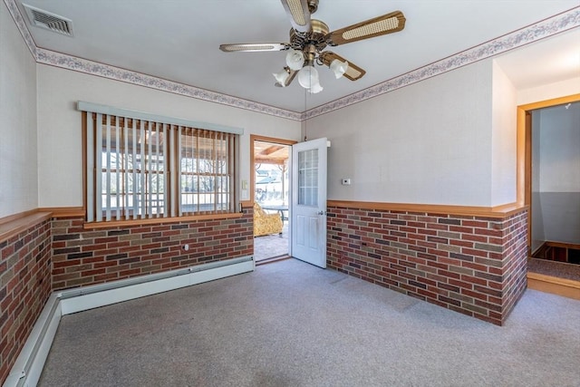 carpeted empty room featuring crown molding, a ceiling fan, a baseboard radiator, brick wall, and visible vents