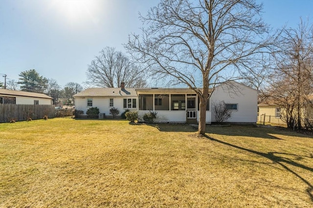 back of property with a chimney, a sunroom, fence, and a lawn