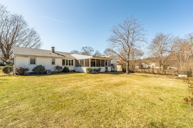 rear view of house featuring a sunroom, fence, a lawn, central AC unit, and a chimney