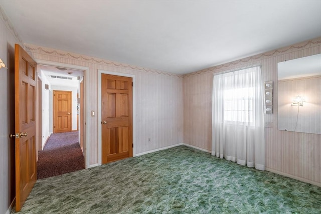 carpeted empty room featuring wallpapered walls, baseboards, and visible vents