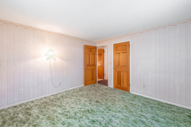 carpeted spare room with baseboards and wallpapered walls