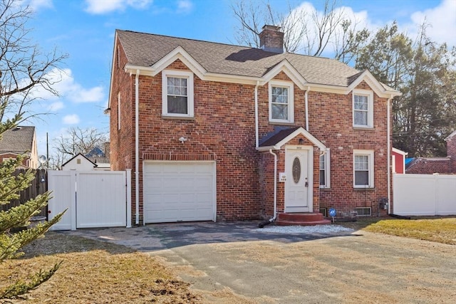 view of front of property featuring brick siding, a chimney, aphalt driveway, and fence