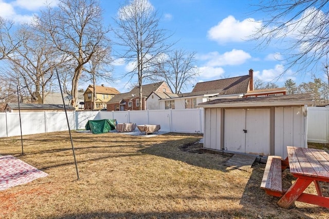 view of yard with an outdoor structure, a fenced backyard, and a storage shed