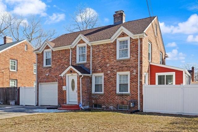 view of front of home with brick siding, fence, concrete driveway, a front yard, and a chimney