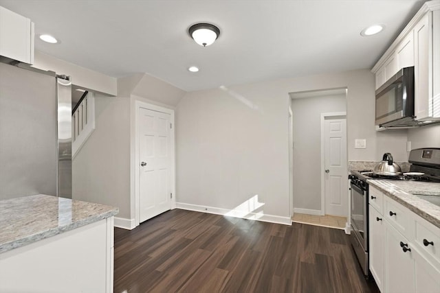 kitchen with dark wood-type flooring, white cabinets, light stone countertops, and appliances with stainless steel finishes