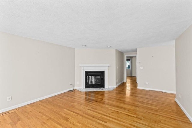 225 Lincoln St Unit G3, Duxbury, MA 02332 - unfurnished living room featuring light wood finished floors, a fireplace with flush hearth, and a textured ceiling