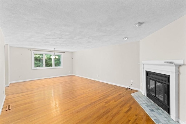 225 Lincoln St Unit G3, Duxbury, MA 02332 - unfurnished living room featuring a textured ceiling, a fireplace with flush hearth, and light wood-style floors