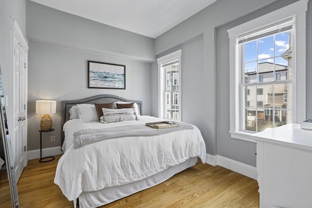 bedroom featuring light wood finished floors and baseboards