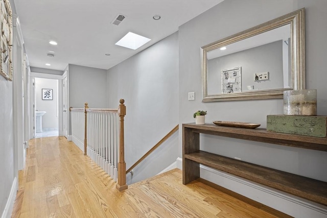 hall featuring a skylight, recessed lighting, visible vents, light wood-style floors, and an upstairs landing