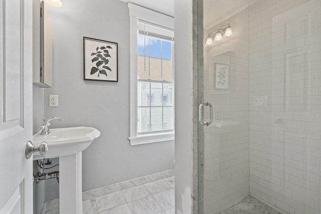 bathroom featuring marble finish floor, a stall shower, and baseboards