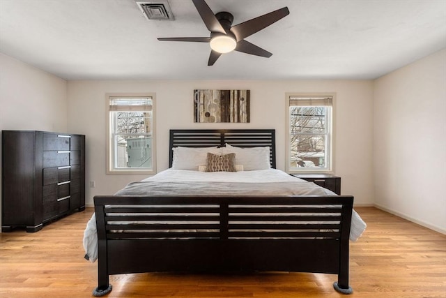 bedroom featuring ceiling fan, multiple windows, and light wood-type flooring