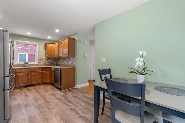 kitchen featuring stainless steel appliances, sink, backsplash, and light wood-type flooring