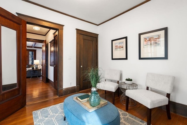 sitting room featuring dark wood-style floors, baseboards, and crown molding