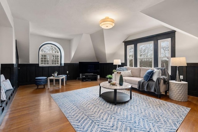 living area with vaulted ceiling, wainscoting, and wood finished floors