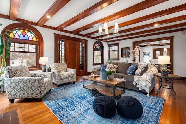 living room with baseboards, beamed ceiling, hardwood / wood-style flooring, and a notable chandelier