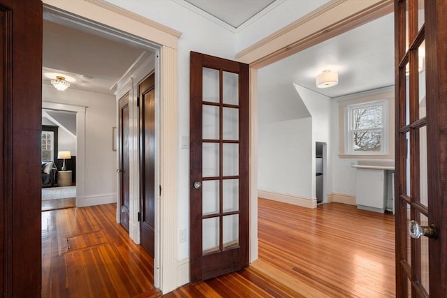 hall featuring ornamental molding, hardwood / wood-style flooring, and baseboards