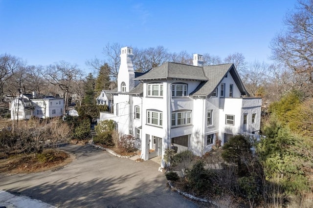 view of side of property with driveway, a chimney, and stucco siding