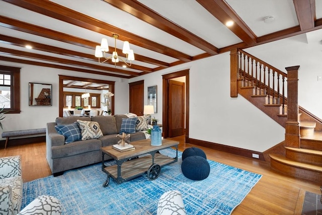 living area with a chandelier, wood finished floors, baseboards, stairs, and beam ceiling