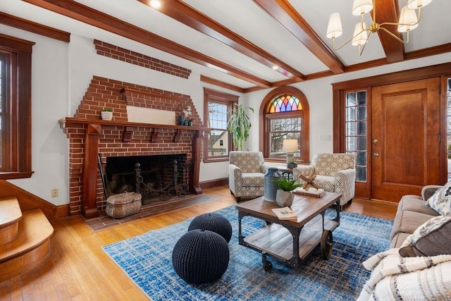 living room featuring a chandelier, a fireplace, baseboards, light wood finished floors, and beamed ceiling