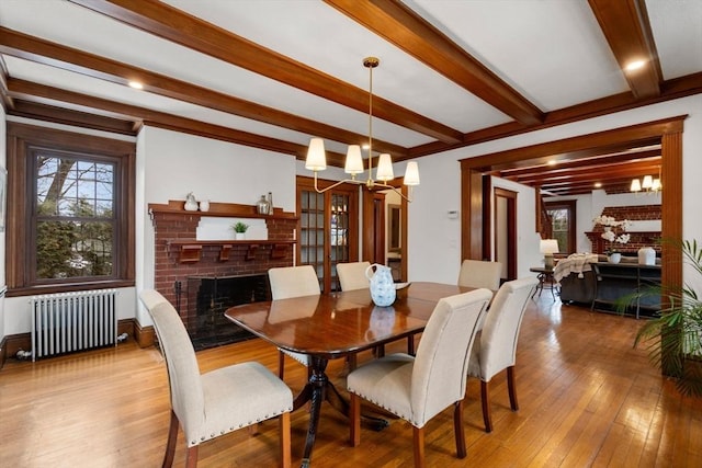 dining space featuring radiator heating unit, a fireplace, and an inviting chandelier