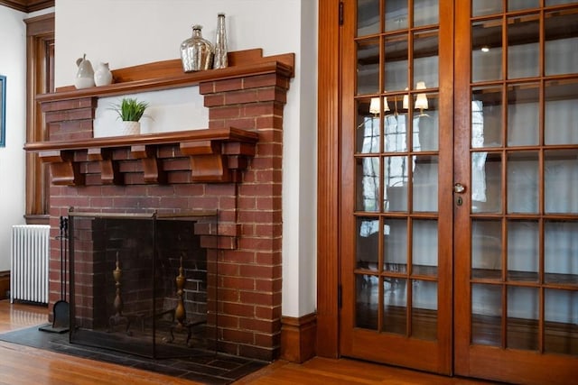 room details featuring a fireplace, radiator heating unit, and wood finished floors