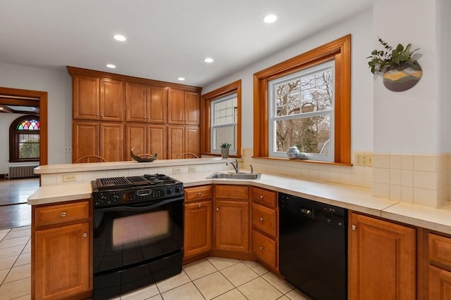 kitchen with brown cabinetry, radiator heating unit, light countertops, black appliances, and a sink