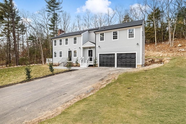 view of front of property featuring aphalt driveway, a front yard, a chimney, and an attached garage