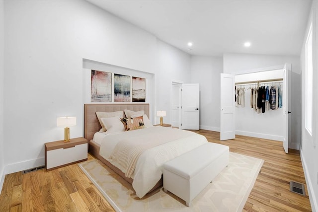 bedroom featuring light wood-type flooring, a closet, and lofted ceiling