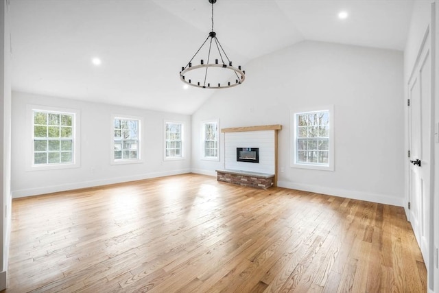 unfurnished living room featuring light hardwood / wood-style floors, a fireplace, an inviting chandelier, and vaulted ceiling