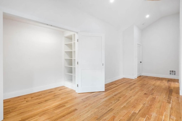 unfurnished room with built in features, light hardwood / wood-style flooring, and vaulted ceiling